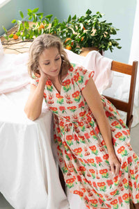 Heidi Florabelle in floral dress, seated near table with plants