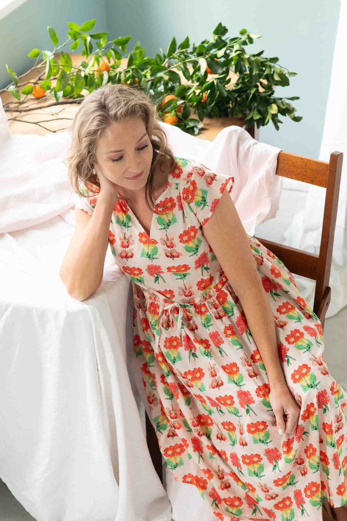 Heidi Florabelle in floral dress, seated near table with plants