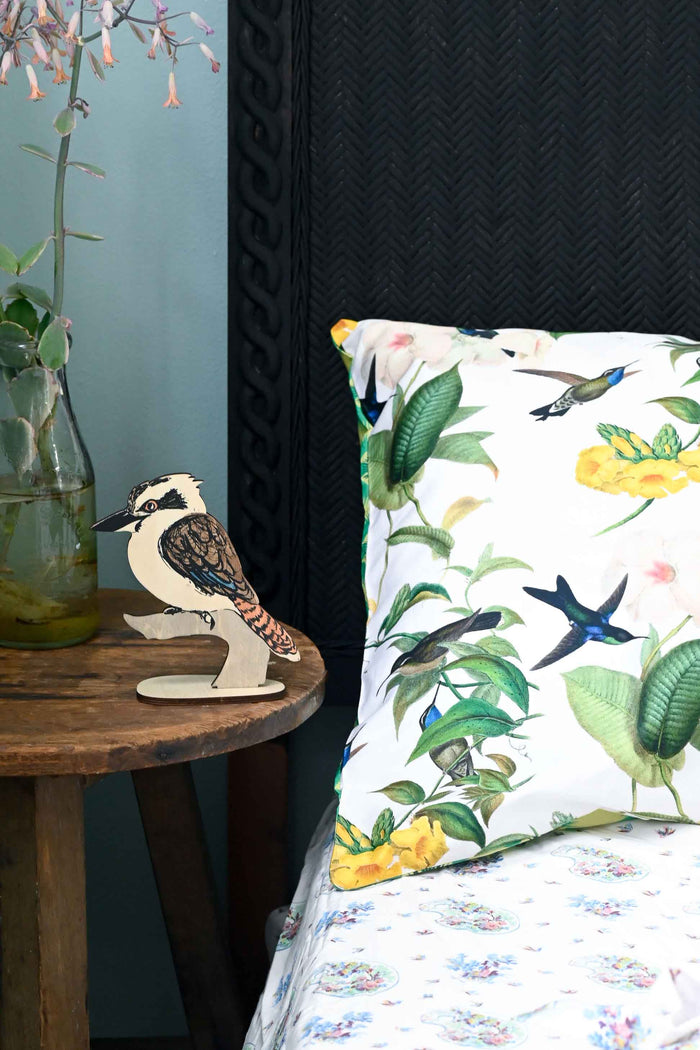Kookaburra stand on table next to floral pillow