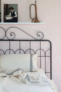 LaBelle Sheets bedding on wrought iron bed, with artwork and trumpet