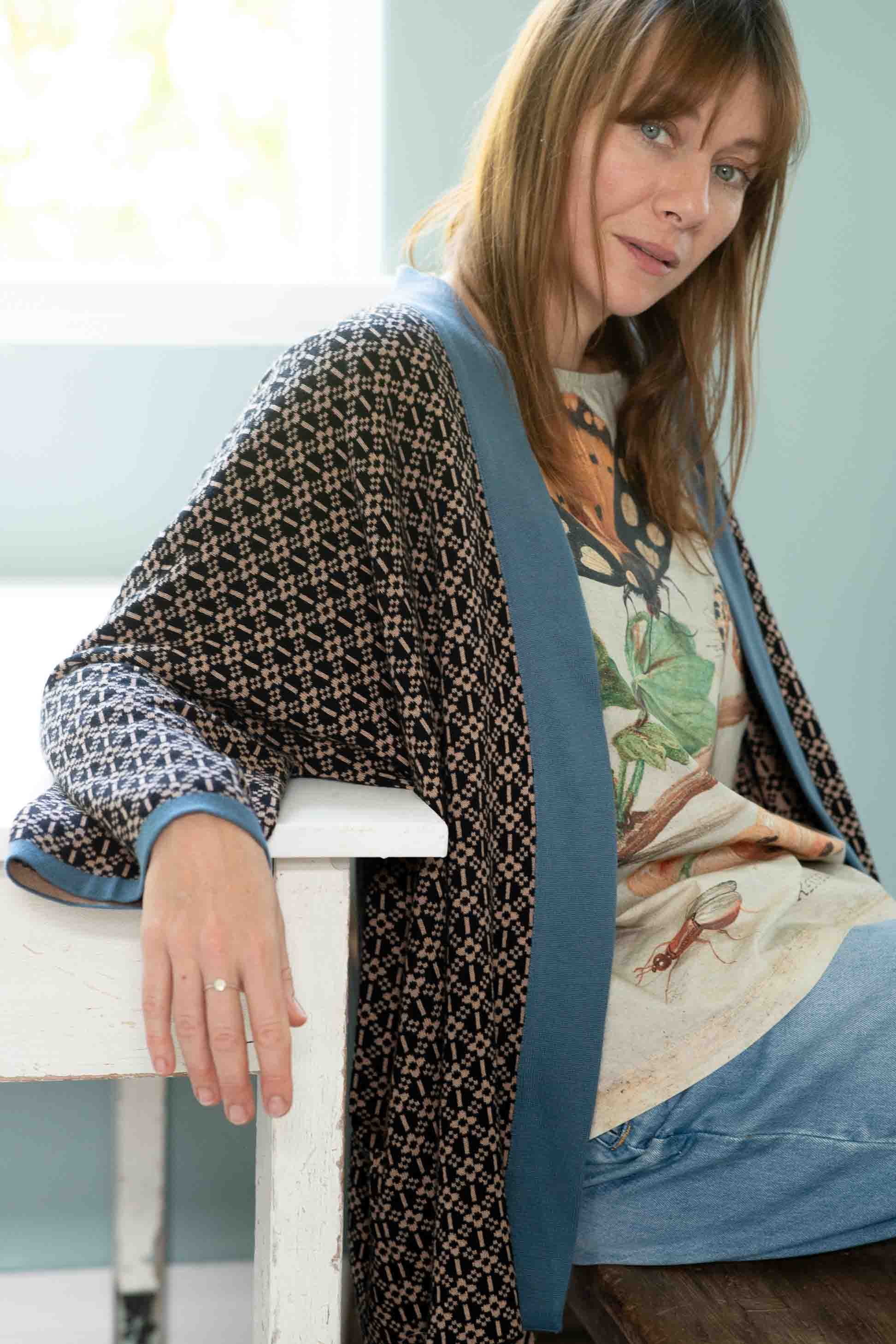 Woman in Lola cardigan and denim with insect print shirt.
