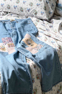 Lucy's patched jeans on floral bedding