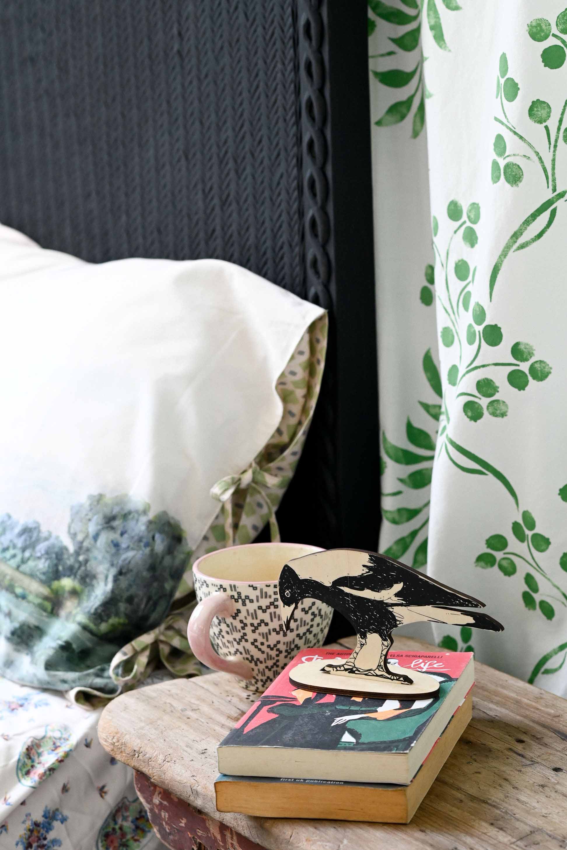 MagpieStandTranquilPillowcase scene with magpie, books, and patterned textiles.