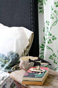 MagpieStandTranquilPillowcase scene with magpie, books, and patterned textiles.