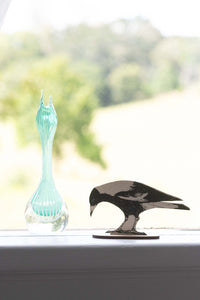 Magpie figurine next to a blue glass vase