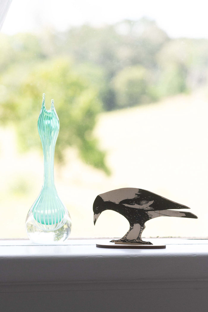Magpie figurine next to a blue glass vase
