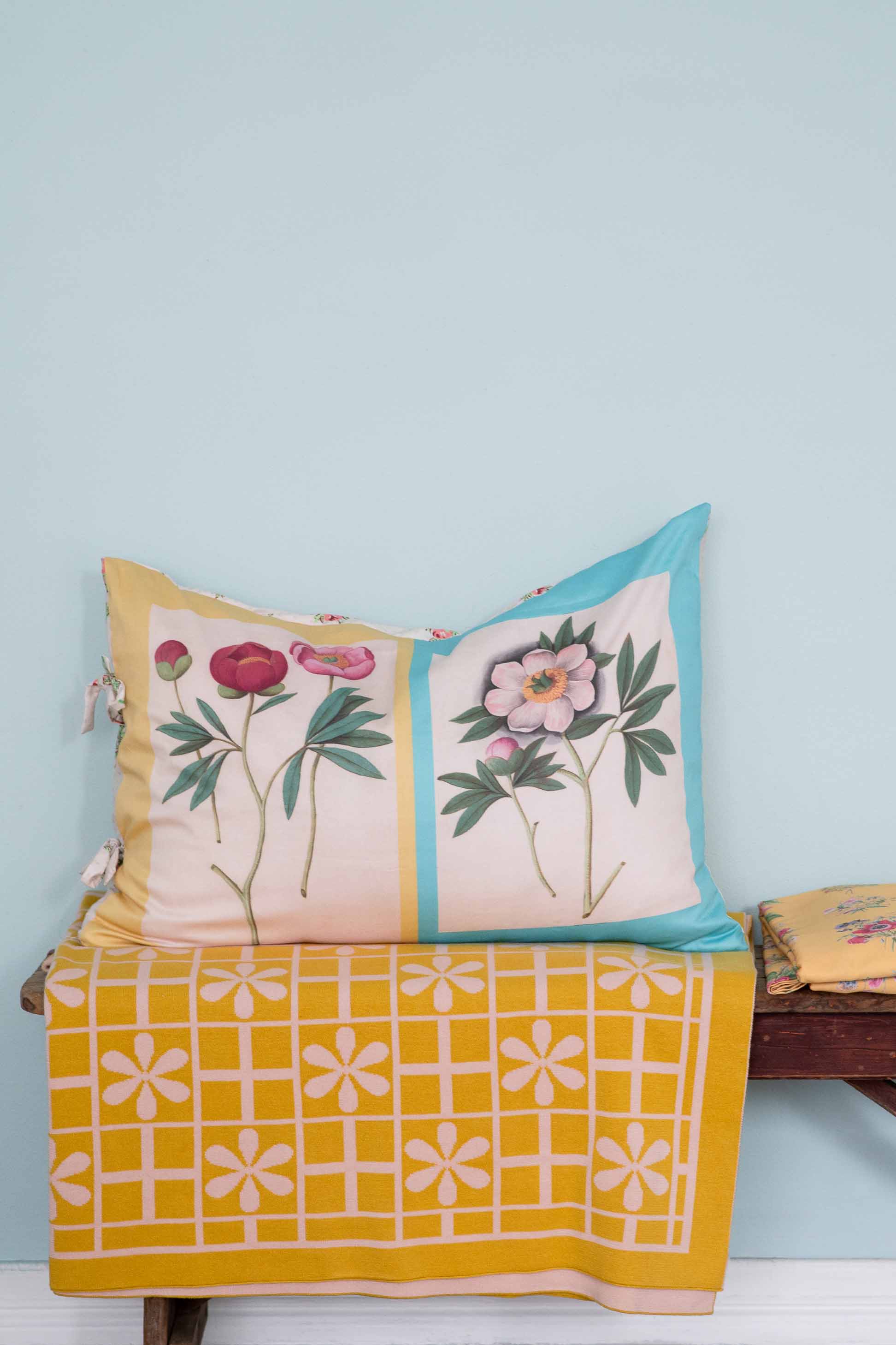 Peony & daisy floral throw pillow on yellow blanket