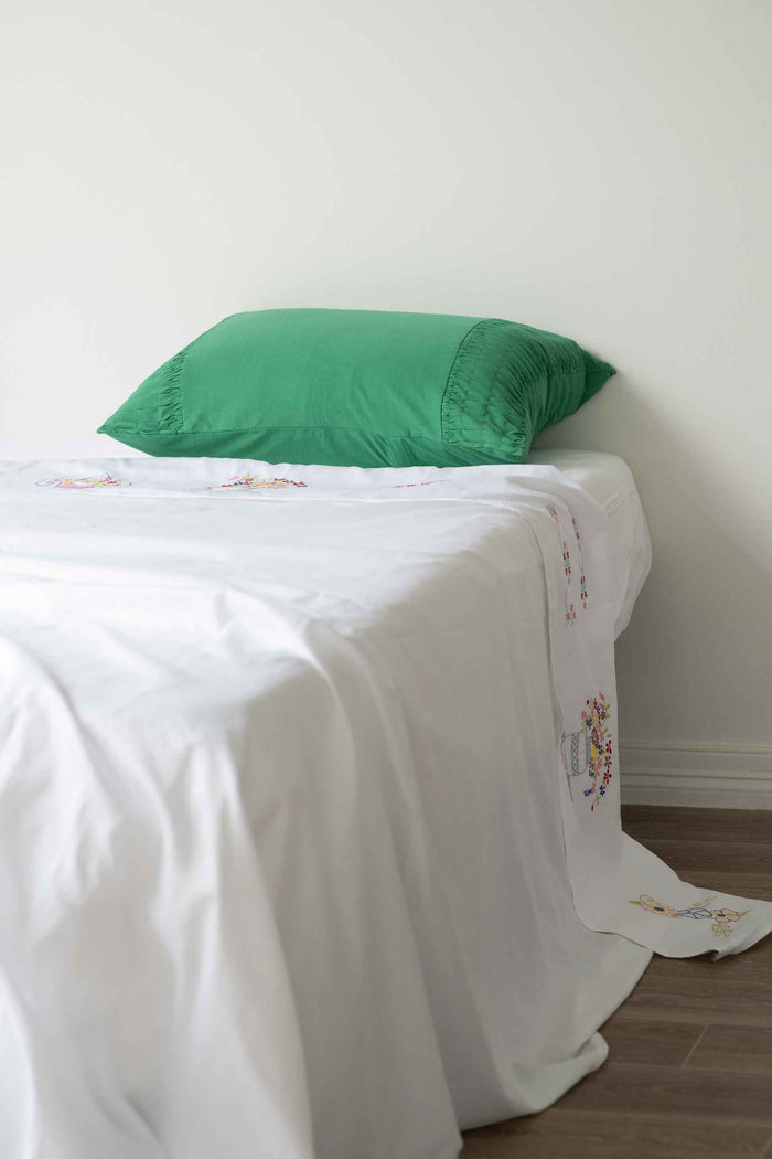 Homespun white sheet with green pillow on bed