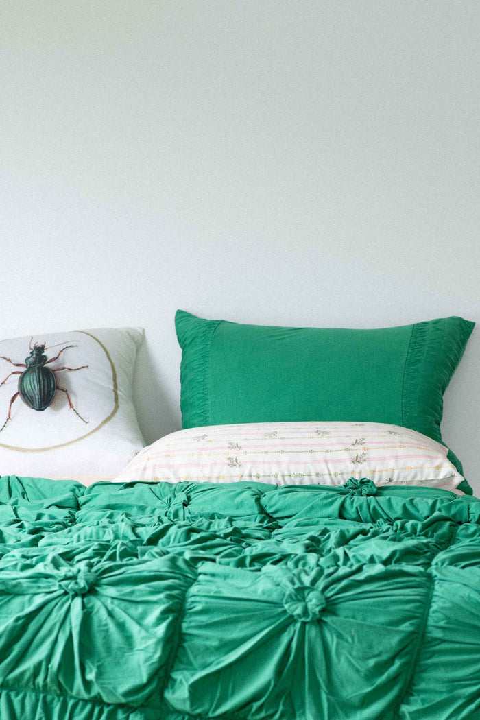 Green rosette moth cushion on bed
