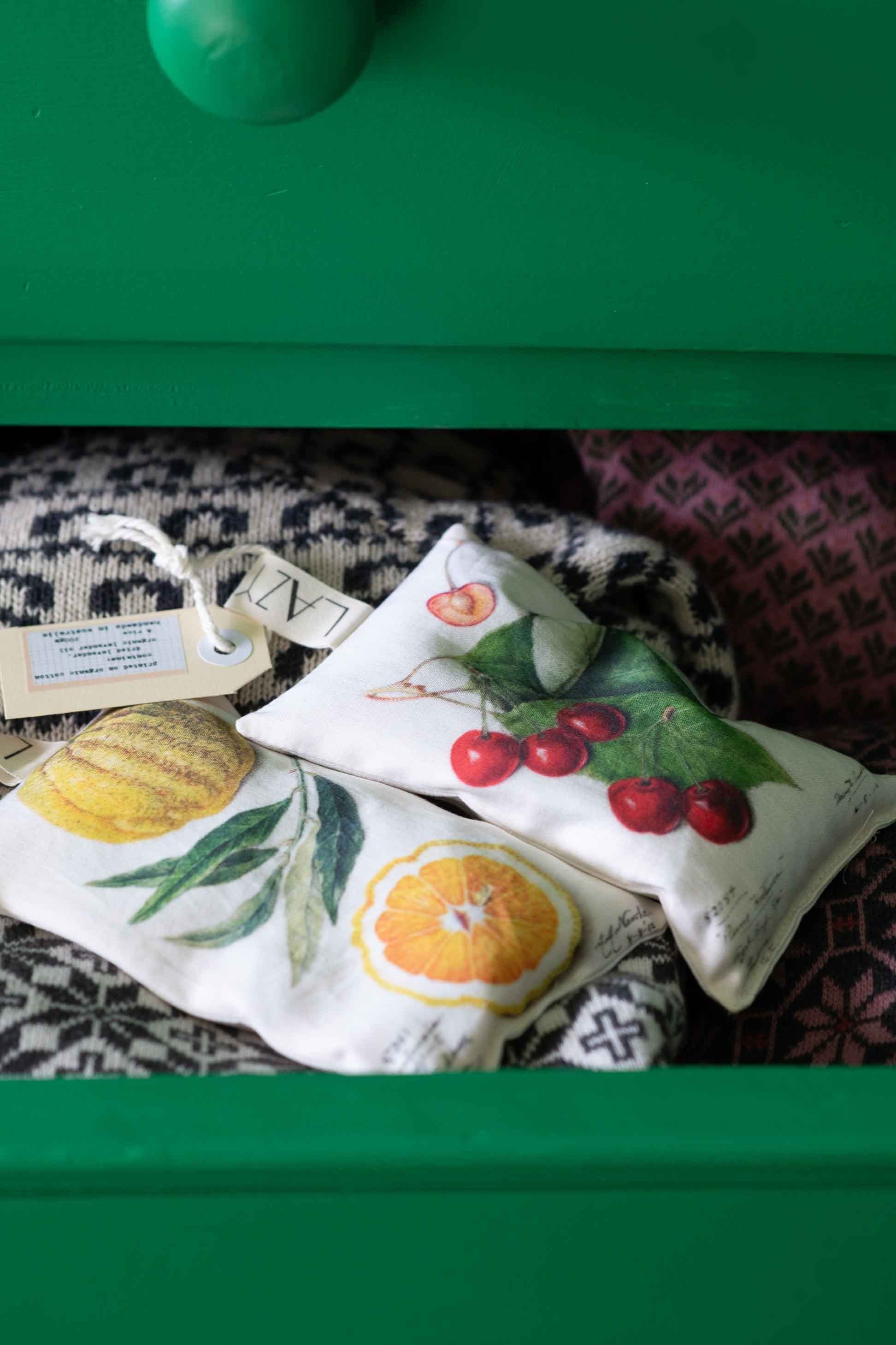Scented sachets with fruit designs in a green drawer.