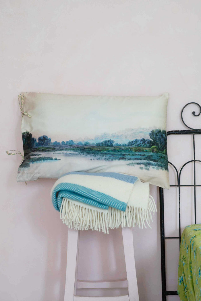 Tranquil landscape pillow & blanket on stool.