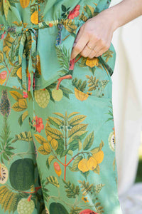 VidaTropics OllieTropics green floral pants with hand in pocket.