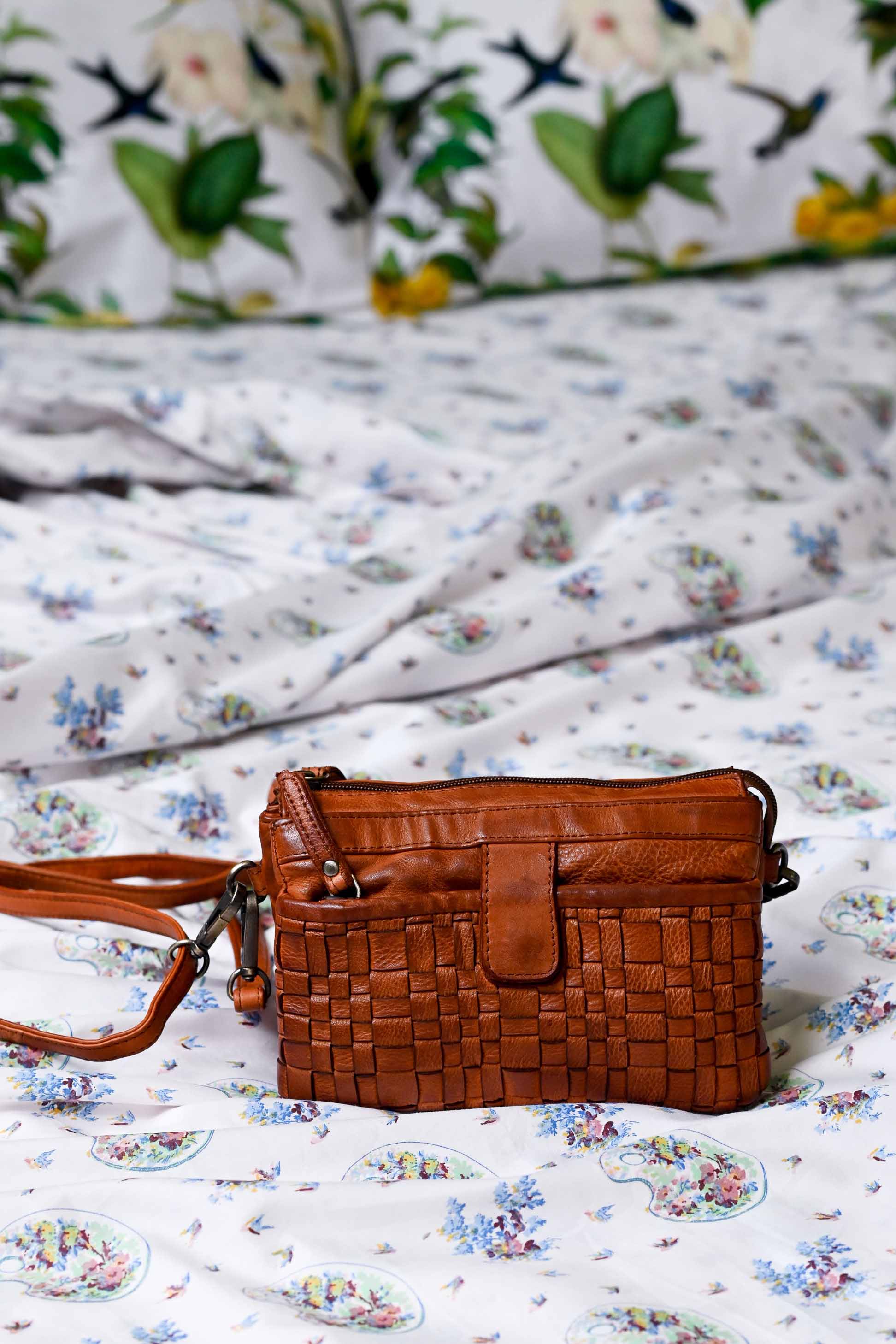 Woven leather bag on floral bedding